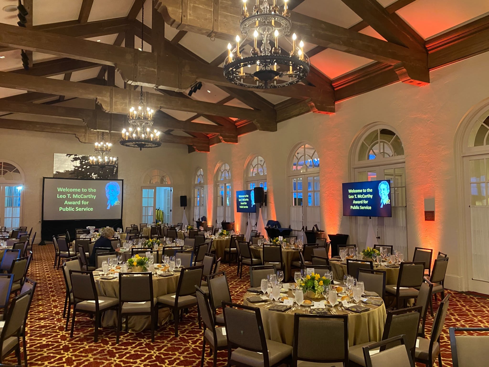 Ballroom set for an awards dinner with screens and uplighting
